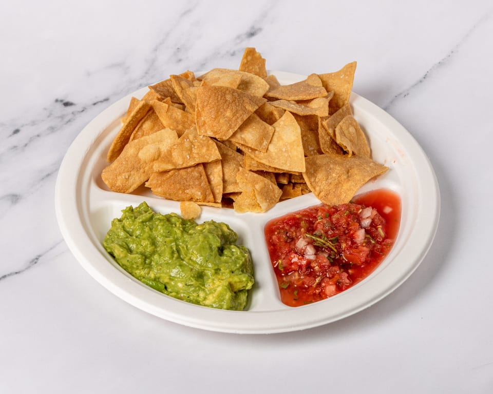 A white segmented plate filled with crispy tortilla chips, guacamole, and fresh salsa.