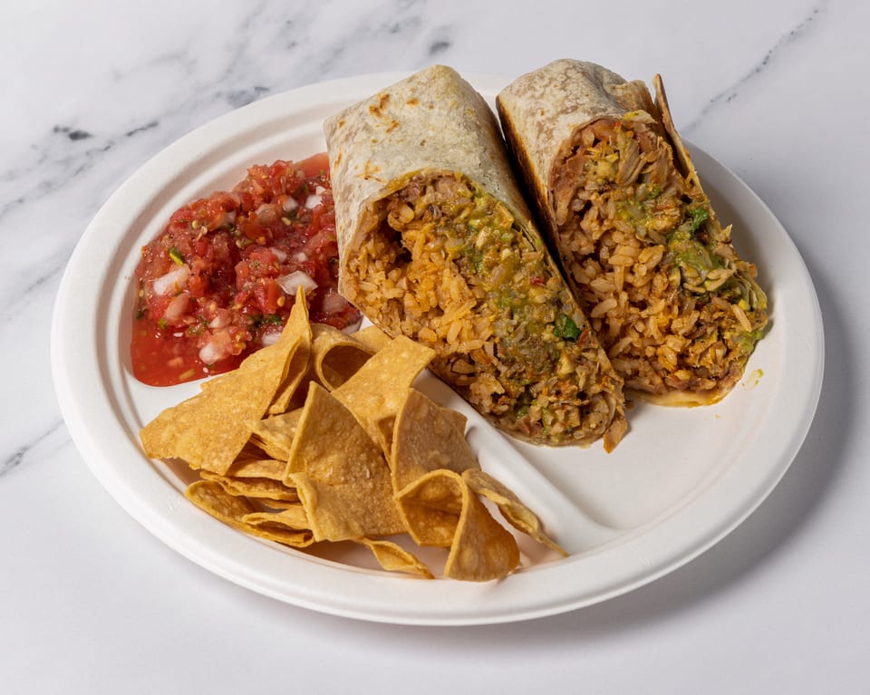Two large burritos, cut in half, with a side of salsa and tortilla chips on a white plate.