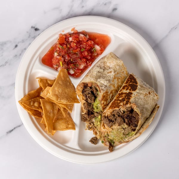 Two burritos with steak, rice, and guacamole, served with tortilla chips and salsa on a white plate.