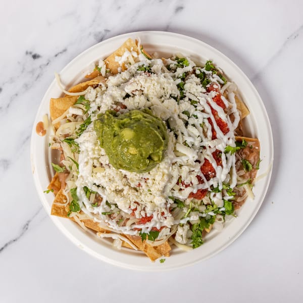Overhead view of a plate of nachos with guacamole, cheese, salsa, and sour cream.