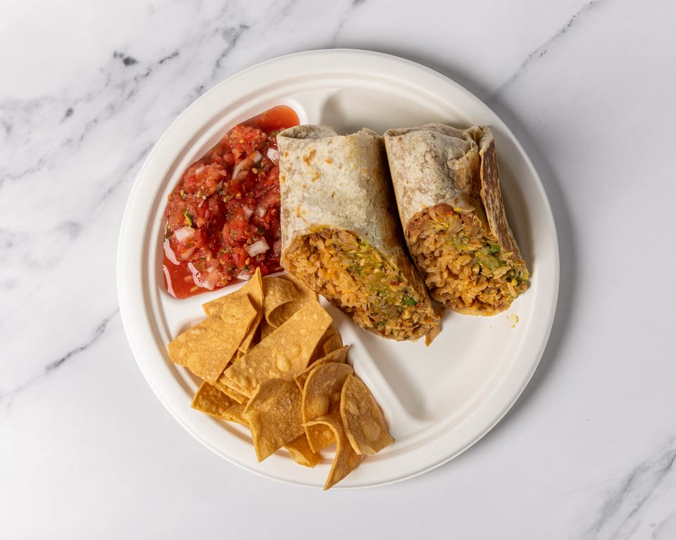 Two burritos cut in half, with salsa and tortilla chips on a white plate.