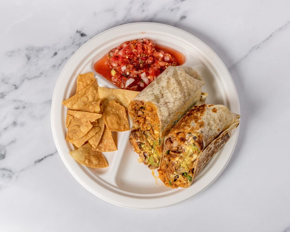 Two burritos, chips, and salsa on a white segmented plate against a marble background.