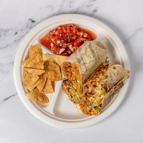 Two burritos, chips, and salsa on a white plate, against a marble background.