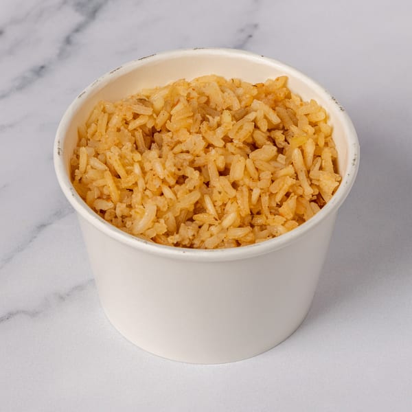 A white paper cup filled with golden-brown fried rice, set against a white marble background.